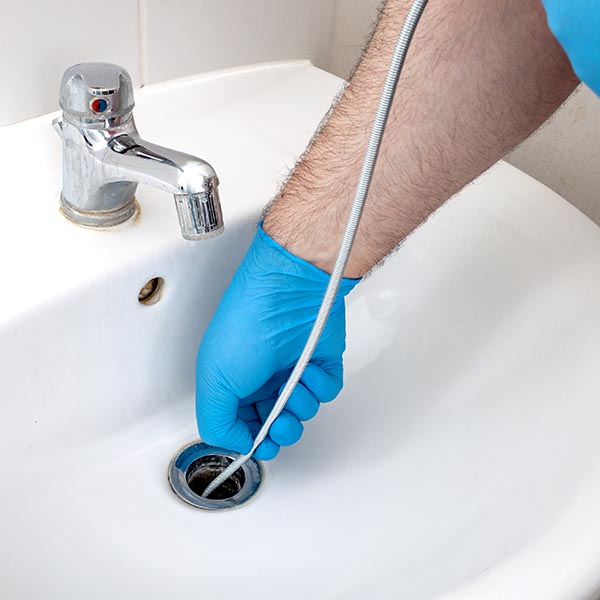 Plumber repairing drain with plumbers snake in residential sink